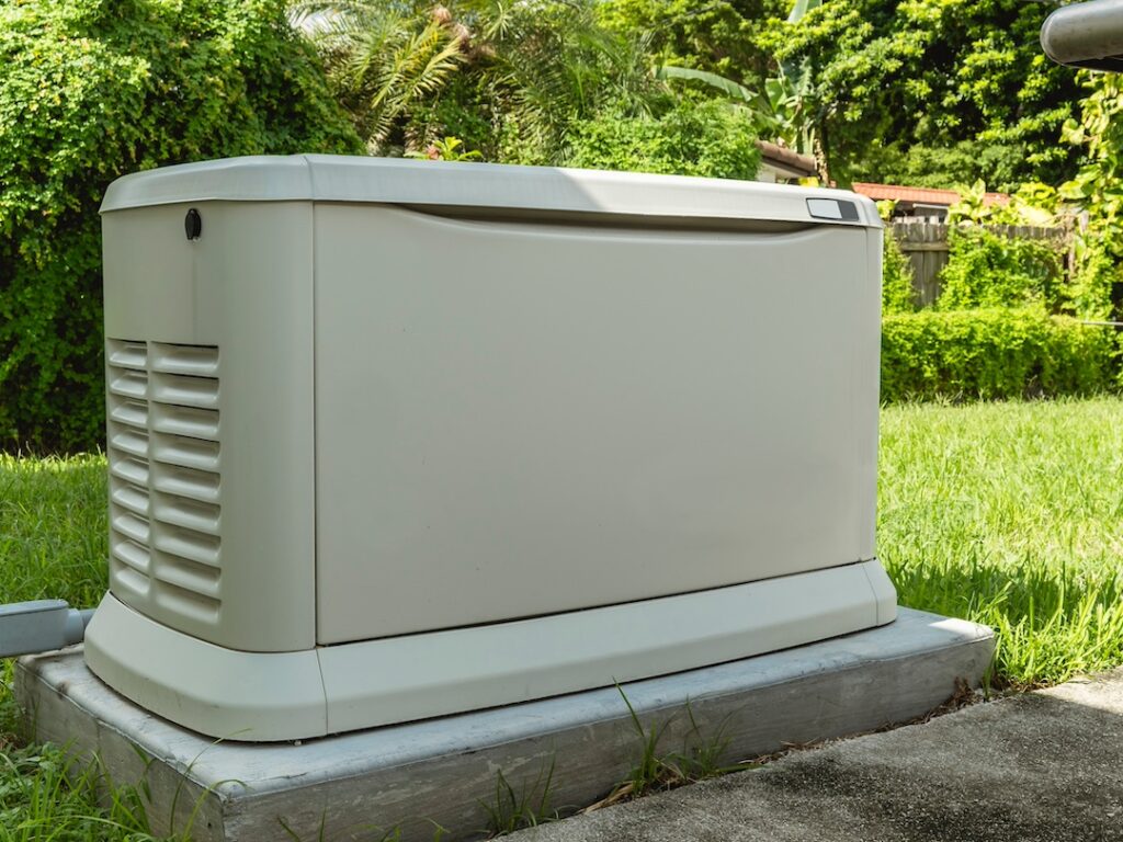 A Home Standby Generator installed at the backyard of a house. An air-cooled natural gas or liquid propane generator for residential use.